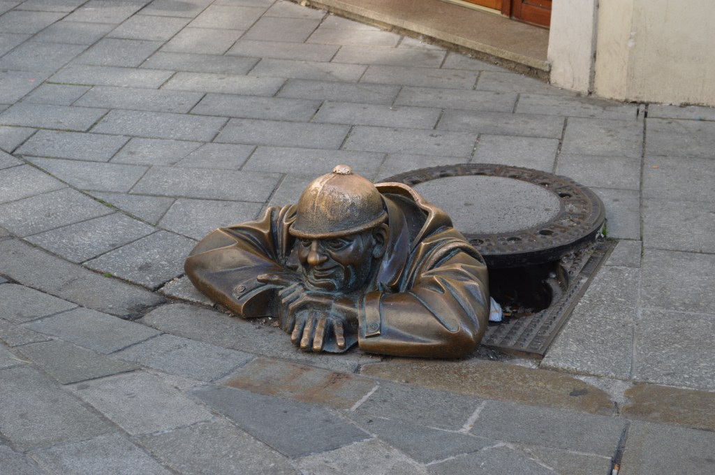 man at work statue peeking from manhole in bratislava