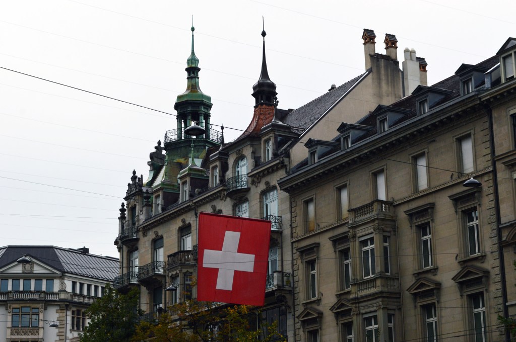 swiss flag hanging in front of historical buildings in zurich