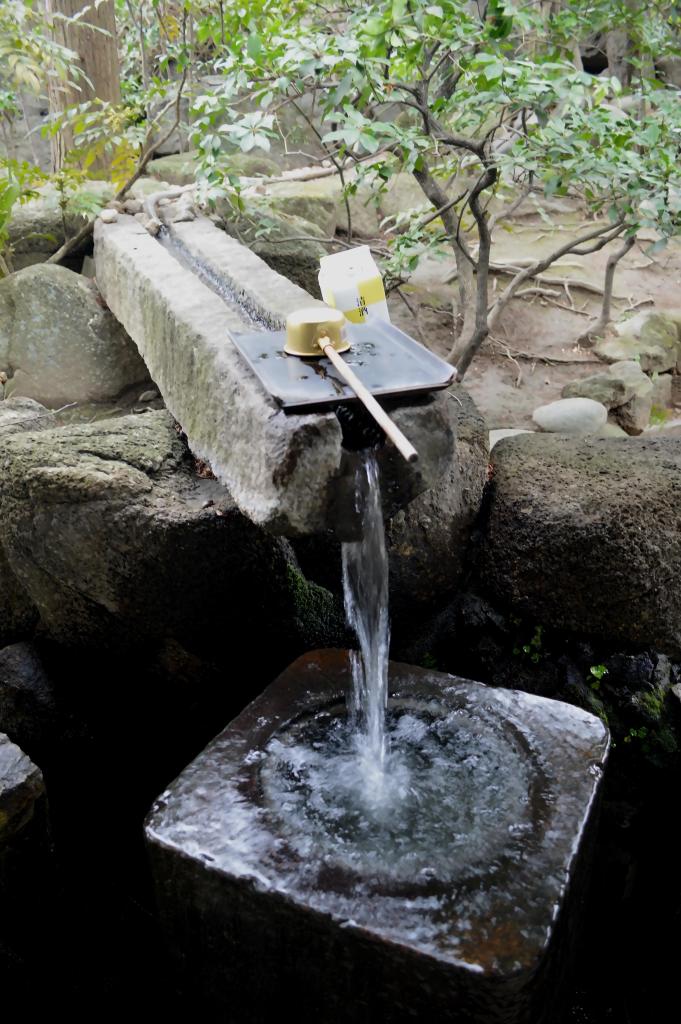 Traditional temizuya purification fountain at a Japanese shrine – Flowing water and ladle for ritual cleansing