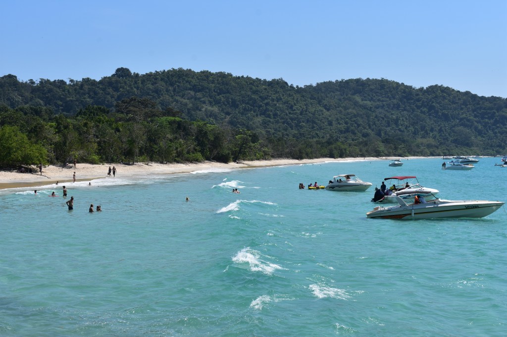 Boats floating near the shore of a tropical beach in Ubatuba, Brazil - Ubatuba stock photos