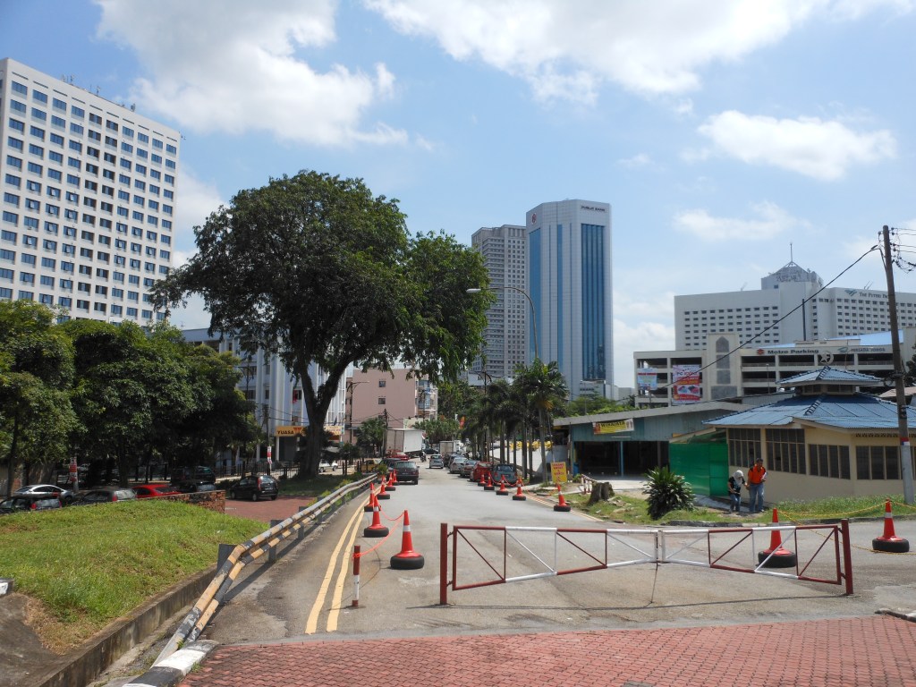 A public space in Johor Bahru with a pedestrian walkway and modern high-rise building