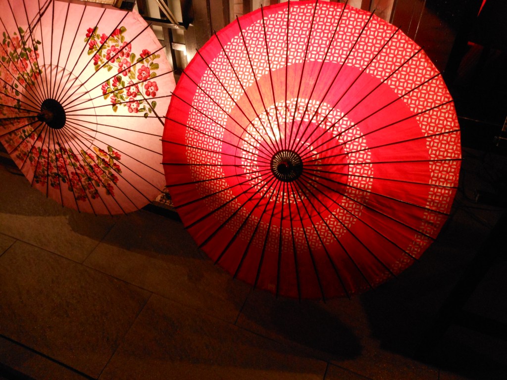Red and white traditional Japanese paper umbrella illuminated at night – A cultural symbol of Japan