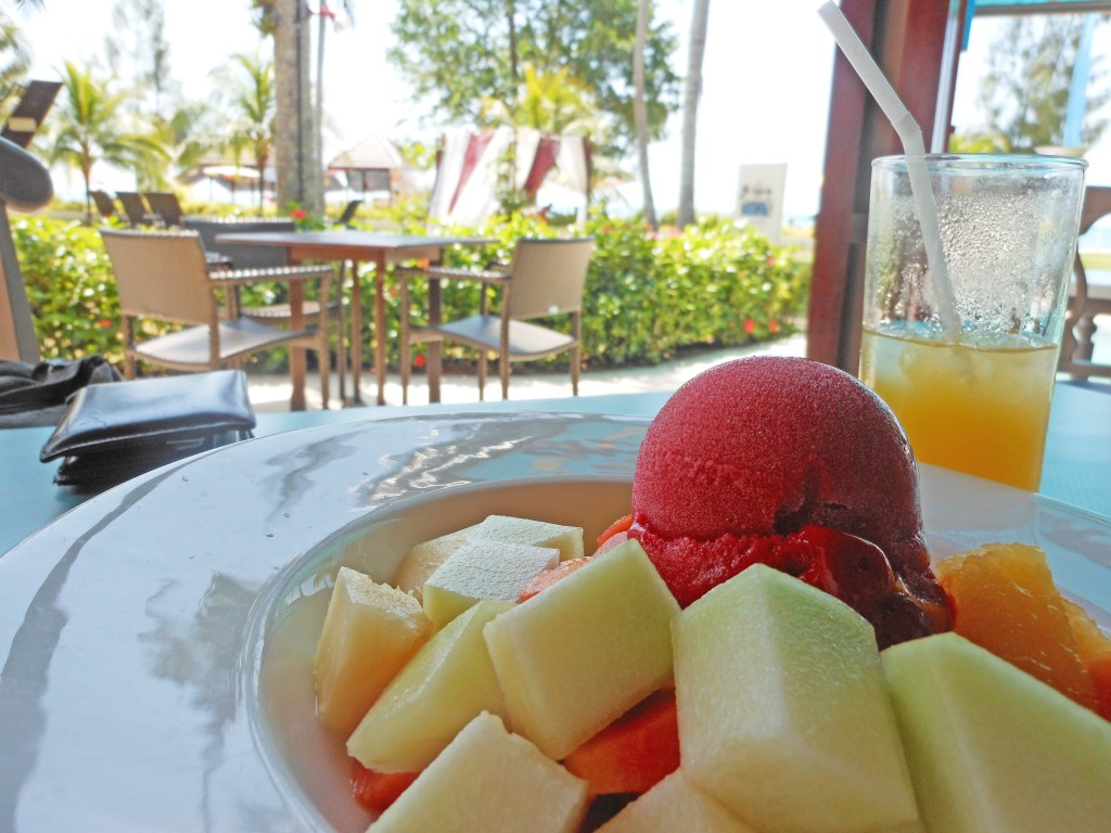 A plate of fresh fruit and sorbet on a table at an outdoor café.