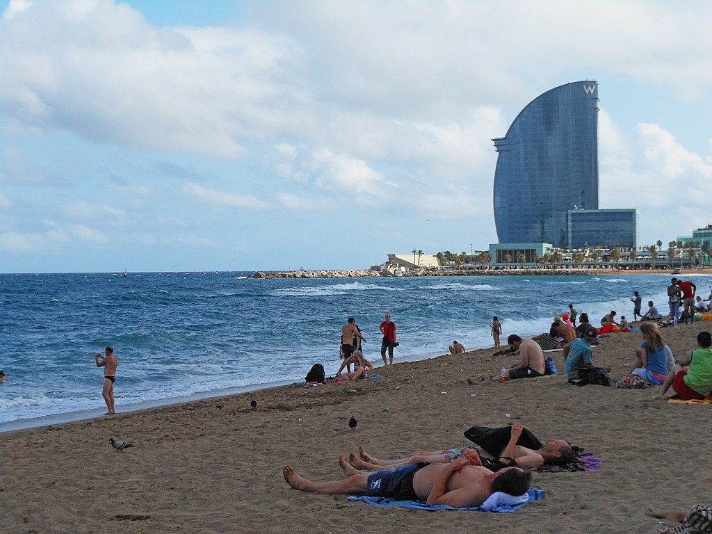 barceloneta beach with people sunbathing and waves – summer in barcelona, spain