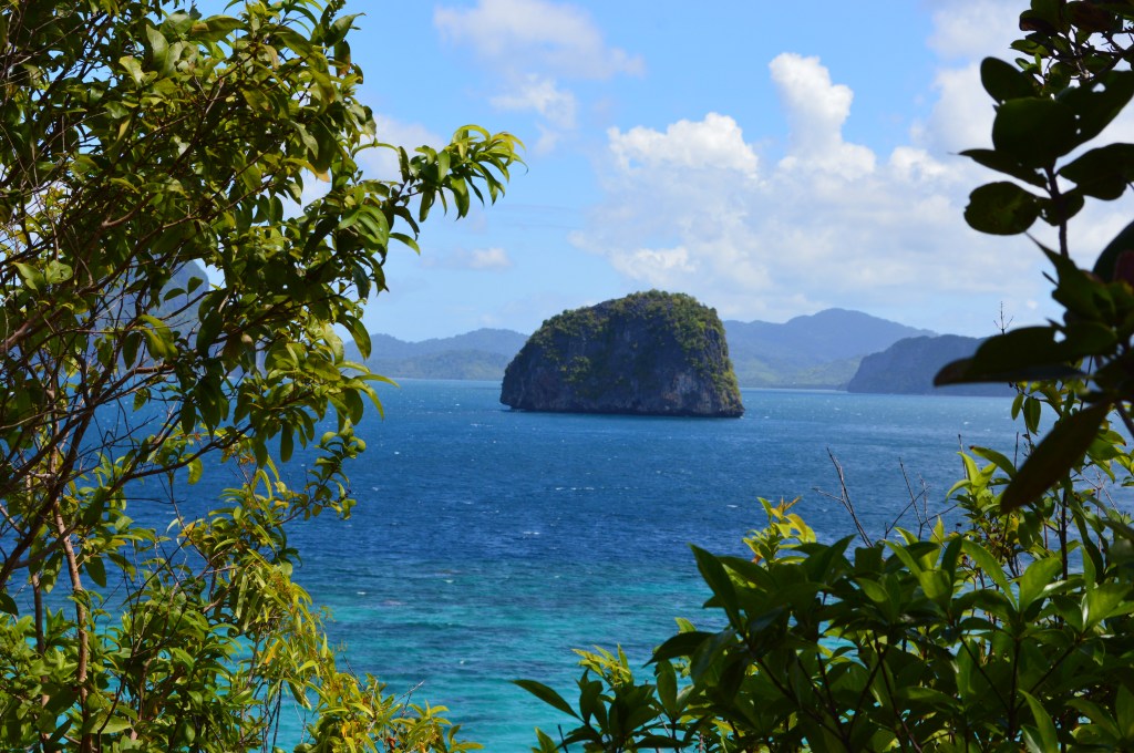 Scenic view of a hidden tropical island surrounded by blue ocean, framed by lush greenery – El Nido stock photo
