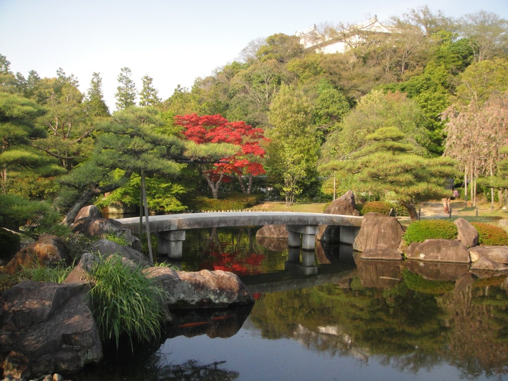 Traditional Japanese garden with a stone bridge and vibrant autumn leaves in Himeji – Himeji stock photos