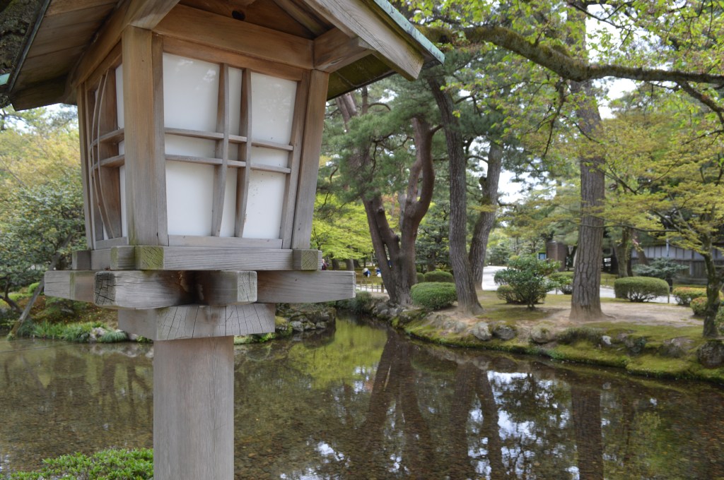 “Traditional wooden lantern beside a reflective pond surrounded by pine trees in a Japanese garden in Ishikawa, Japan.”-Ishikawa stock photos