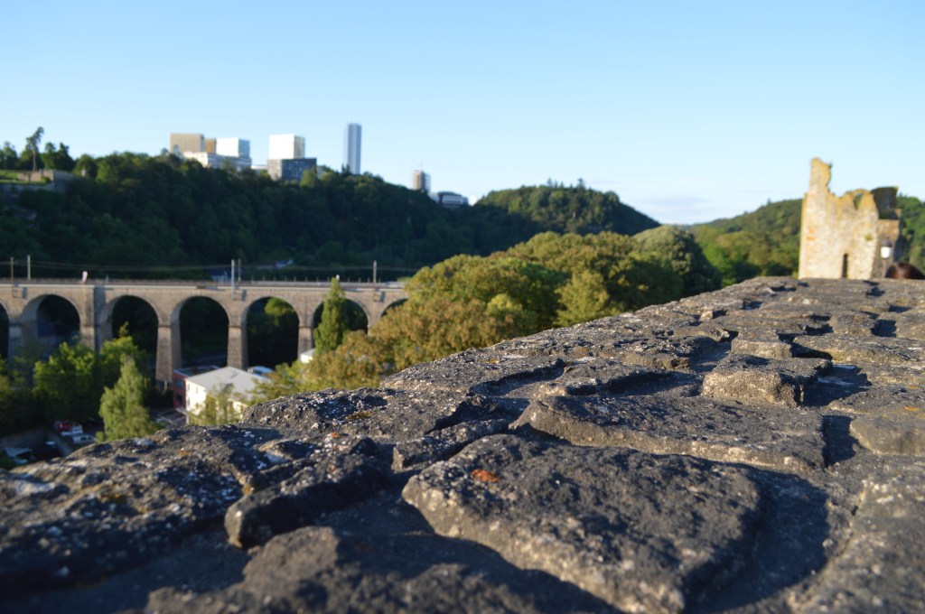 Stone wall with a distant view of Luxembourg city's modern skyline and forested valley -Luxembourg stock photos